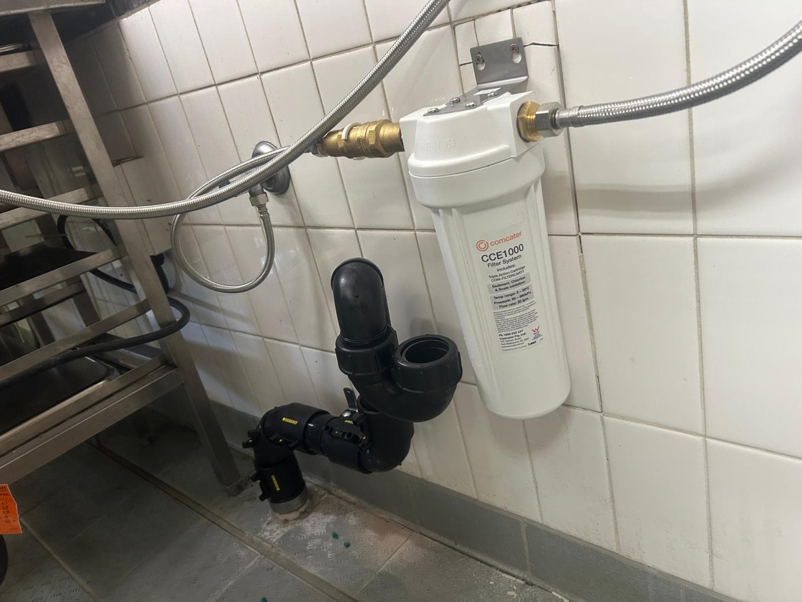 Water filter plumbed in under a bench, with black pipework