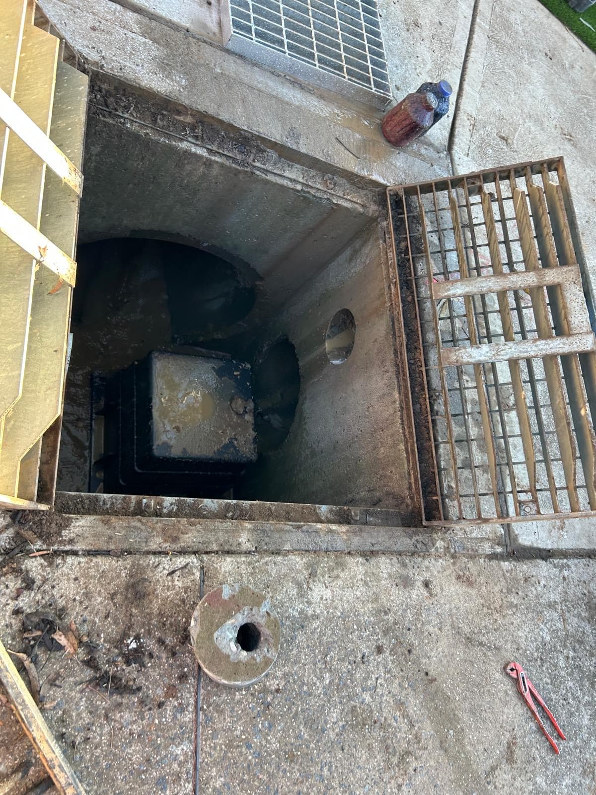 Stormwater pit installation, with the grate lifted and water in the pit