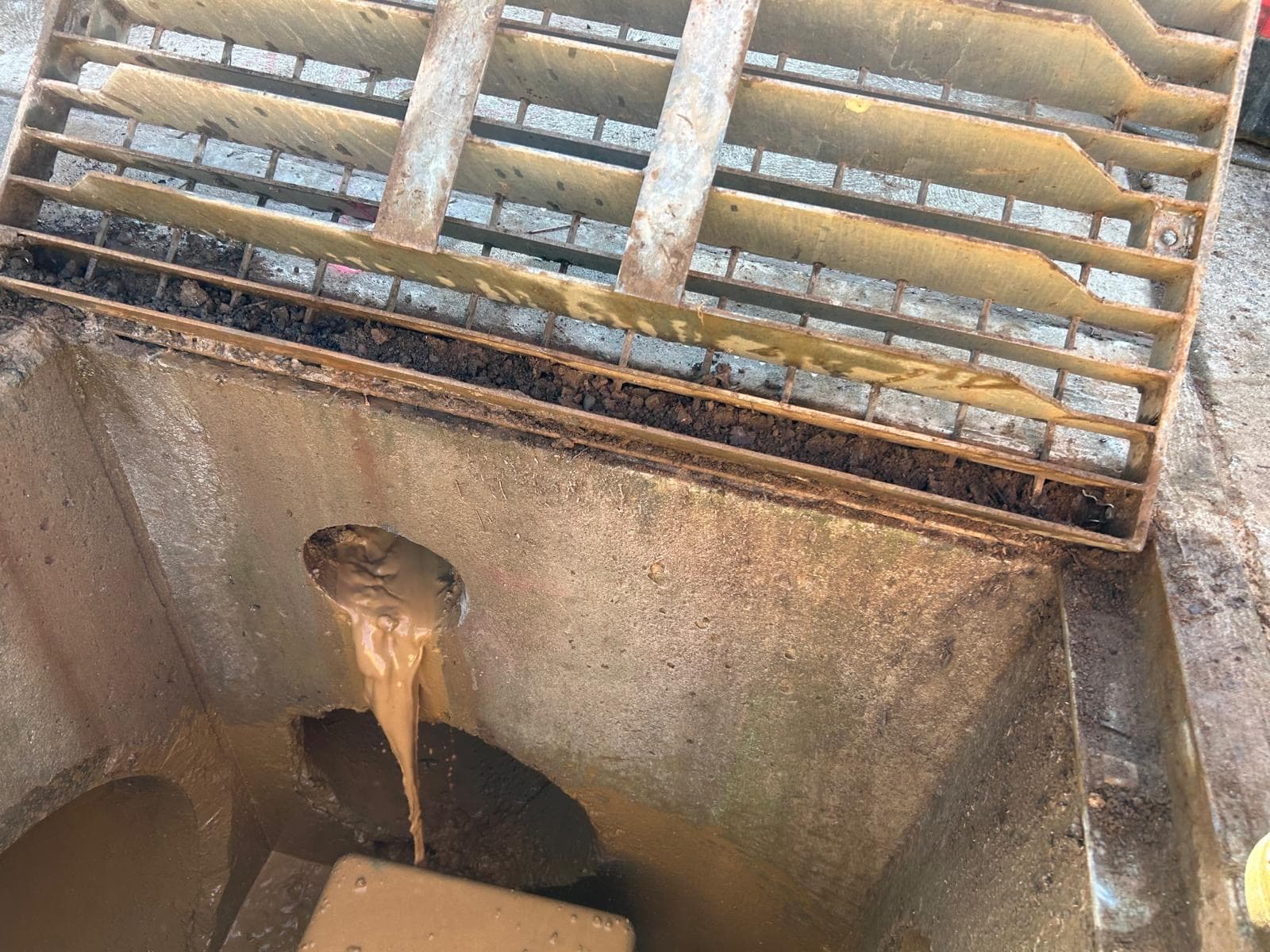 Bore hole through a stormwater pit wall, with slurry pouring out
