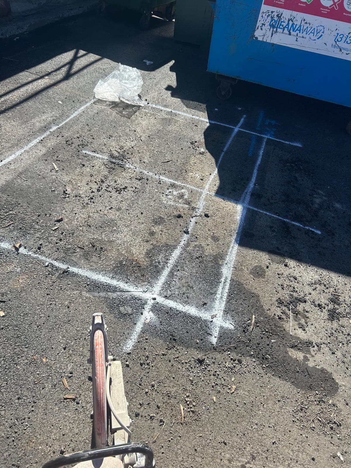 Buried pipe located and marked out in white paint on asphalt
