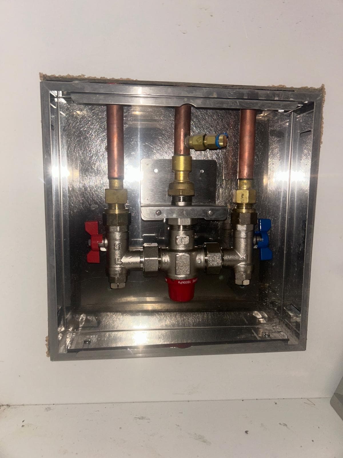 Thermostatic mixing valve (TMV) in a recessed stainless wall box