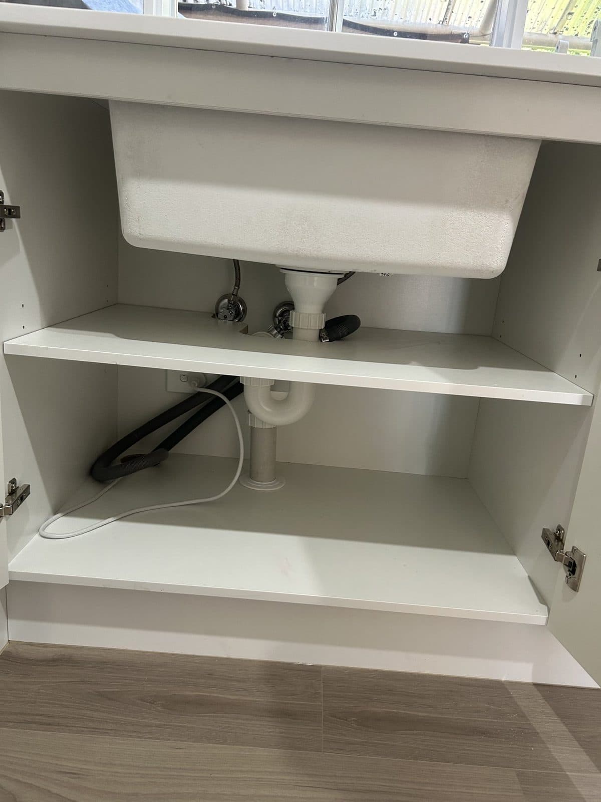 Laundry sink in a white cabinet, with the waste trap and tap connections underneath