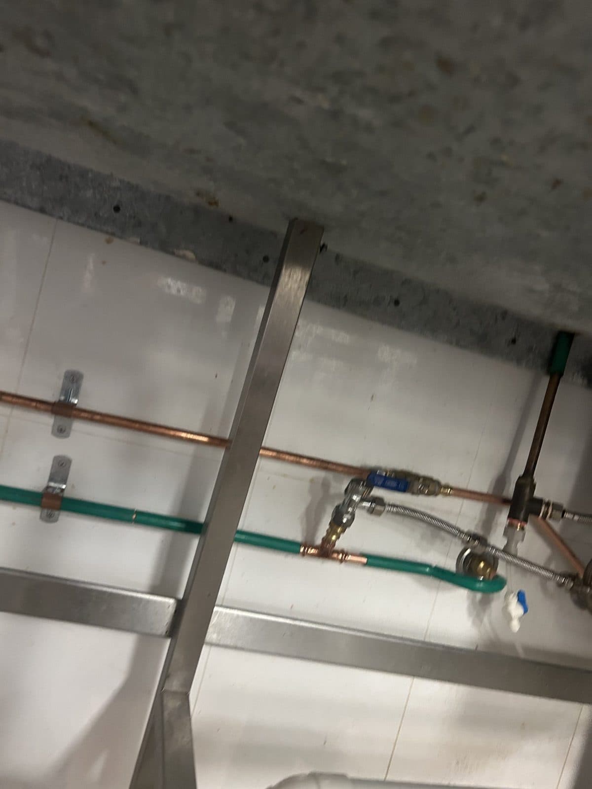 Copper pipework with isolation valves and a braided hose under a benchtop